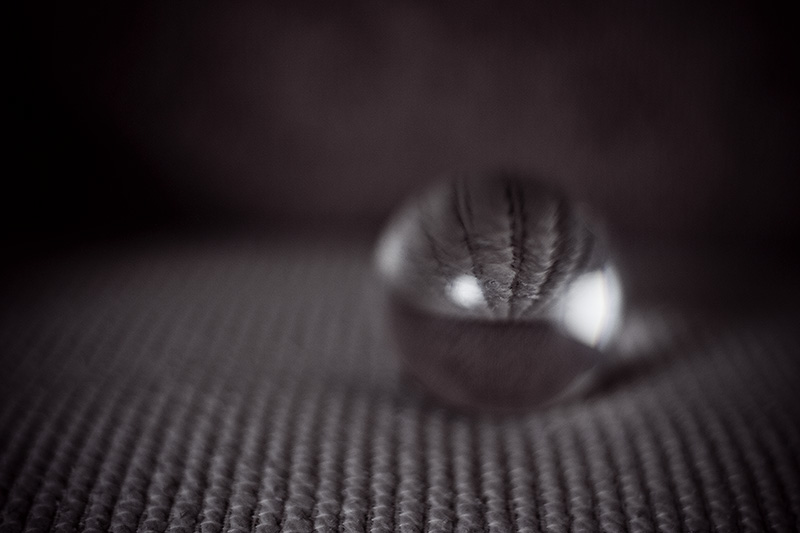 A small crystal ball sitting on the striped surface of a couch cushion.