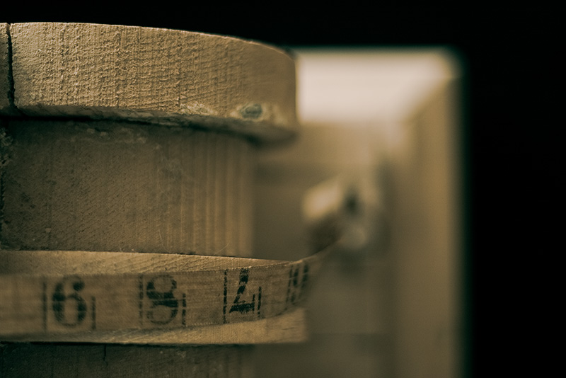 An antique tape measure draped over a wooden corbel.