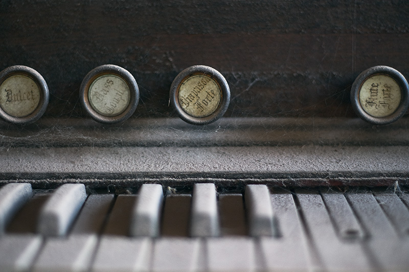 A detailed view of the keys and stops of a dust-covered antique organ.
