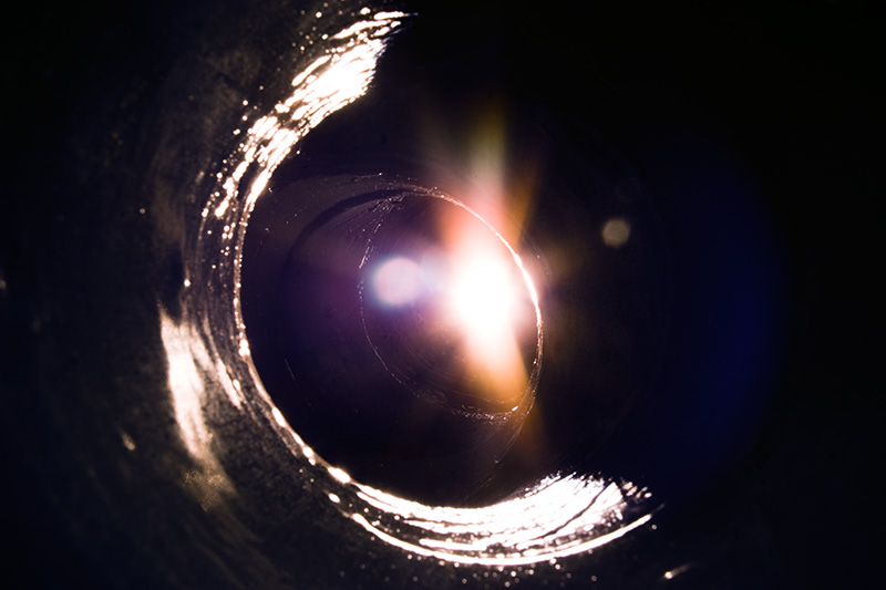 A bright, multi-colored glow comes from around the corner of a dark tunnel.