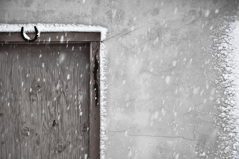 Snowfall built up around a door of a building.