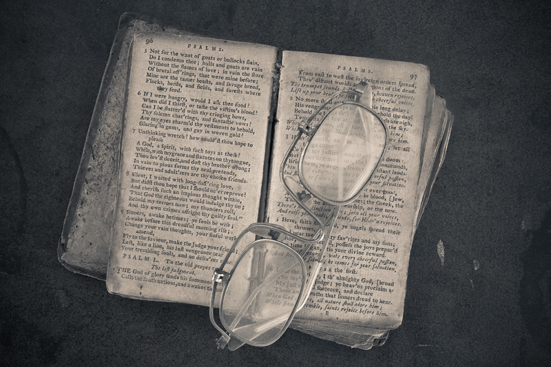 A book of psalms with a pair of folding glasses sitting atop.