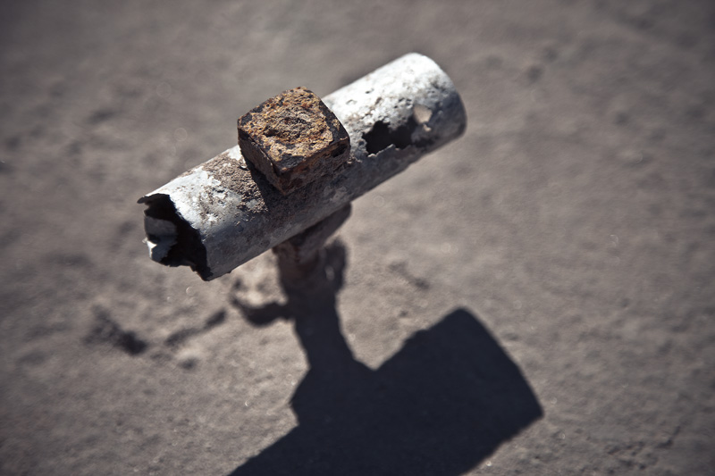 An old, deteriorating metal handle attached to a cement hatch.