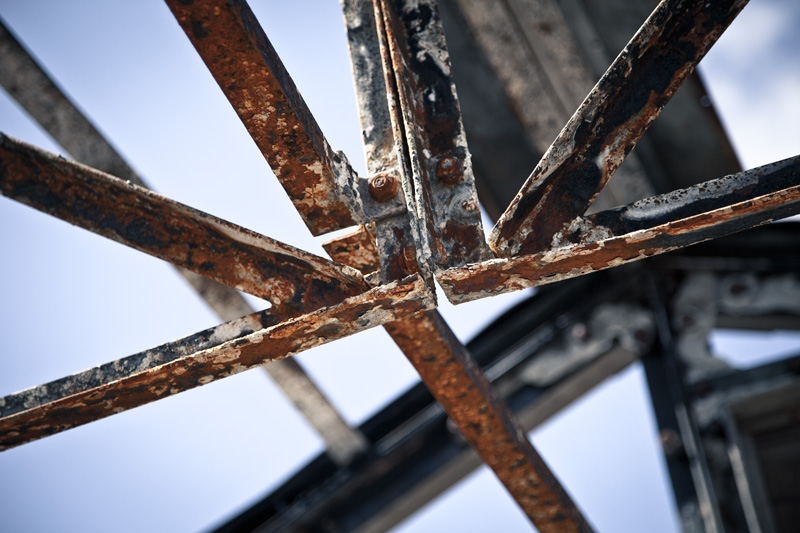 The rusted and burnt structure of an old building atop a peak.