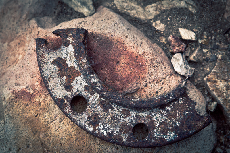 A broken and rusted metal ring in the shape of a crescent.