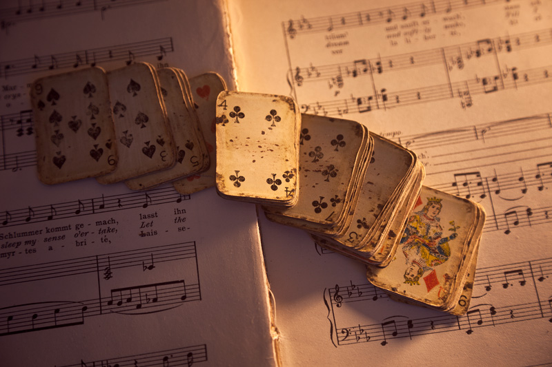 A miniature deck of cards atop sheet music.