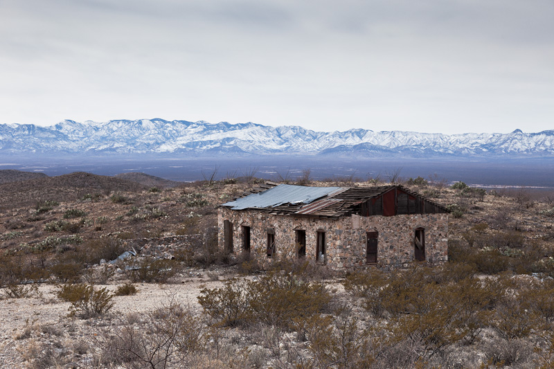 An abandoned building at the Johnny Bull Mine, with the snow-covered Chiricahua Mountains behind.