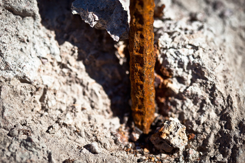 A rusty segment of rebar extending from concrete rubble.
