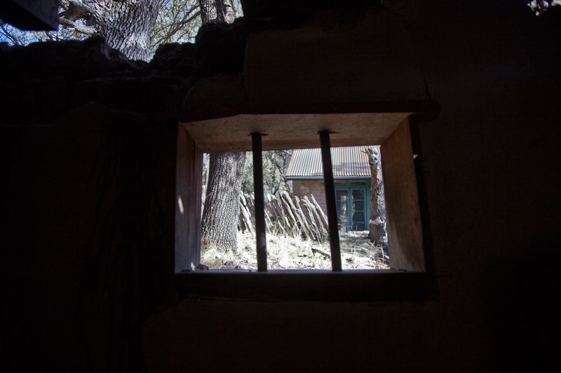 A view through the barred window of a partially collapsed structure.