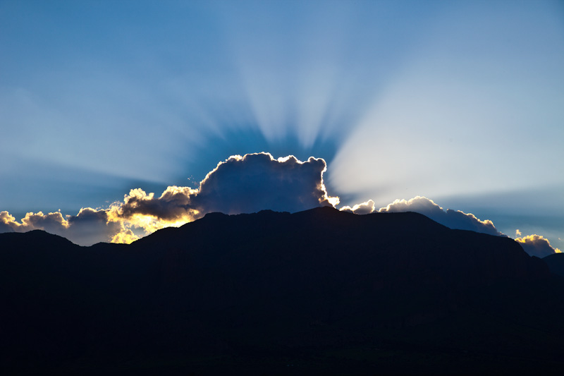 A burst of sunlight from behind a cloud, with a shadow cast by the cloud.
