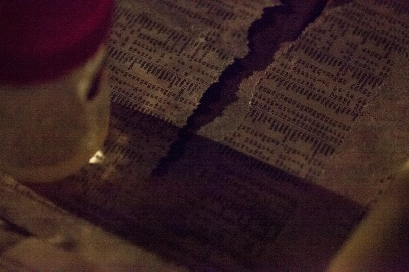 A torn piece of newspaper, partly in shadow.