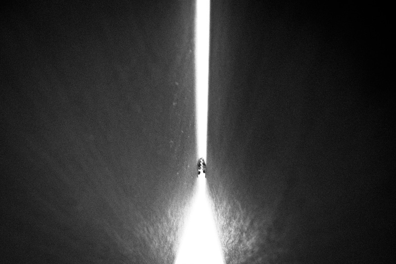 A beam of light rising into the sky out of a pyramidical shape with scary teeth.