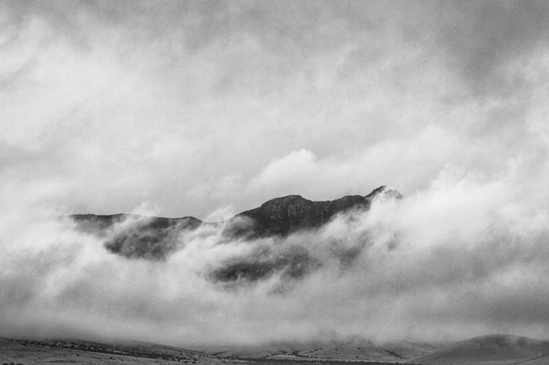 The top of a mountain visible through a hole in the clouds.