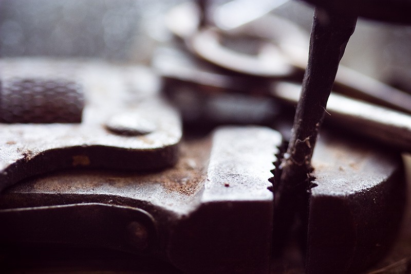 An antique wrench gripping a nail.