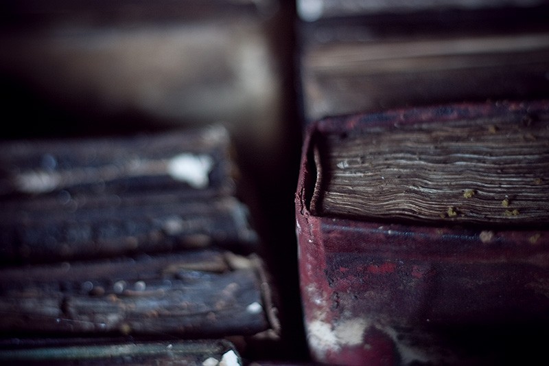 Several decomposing books, one of which is red.