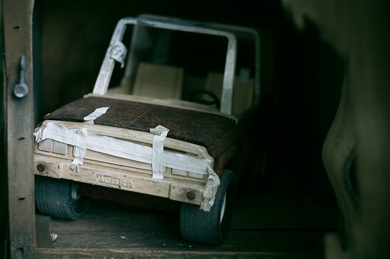 A handmade toy car made of cardboard, inside a cupboard.
