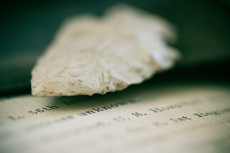 An arrowhead above a diagonal page of printed text.