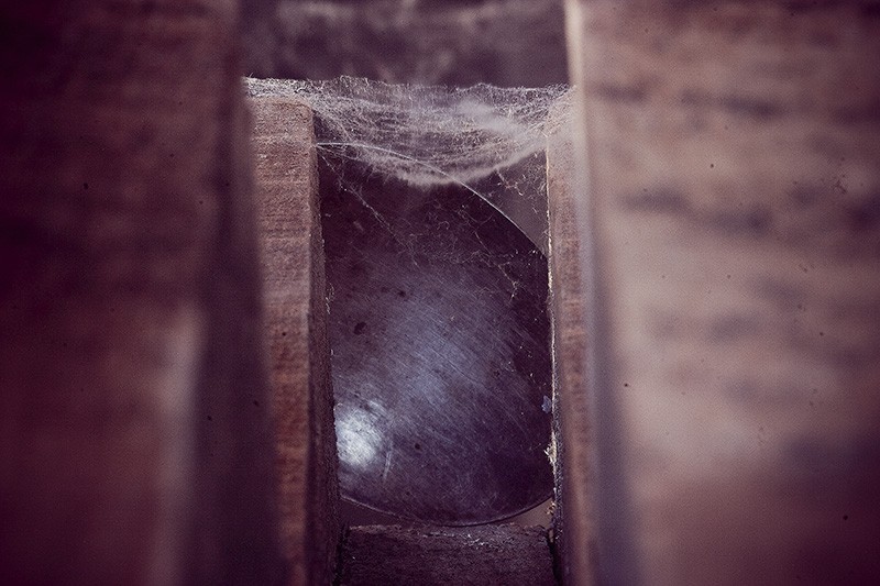 A cobweb-covered corridor with a partially-obscured metallic object at the end.
