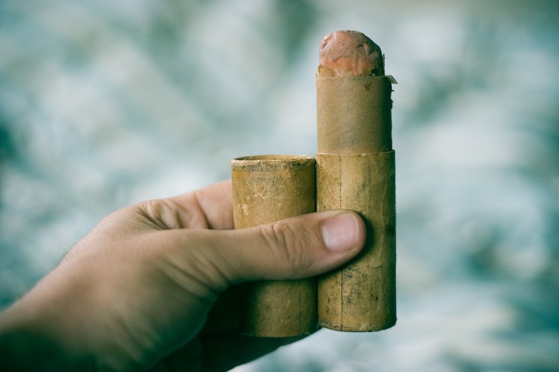 An open cardboard tube, with chalk emerging from the end, held in a hand.