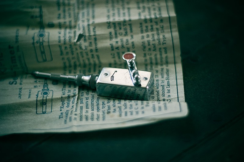 A self-timer device for an old camera, sitting on its instruction sheet.