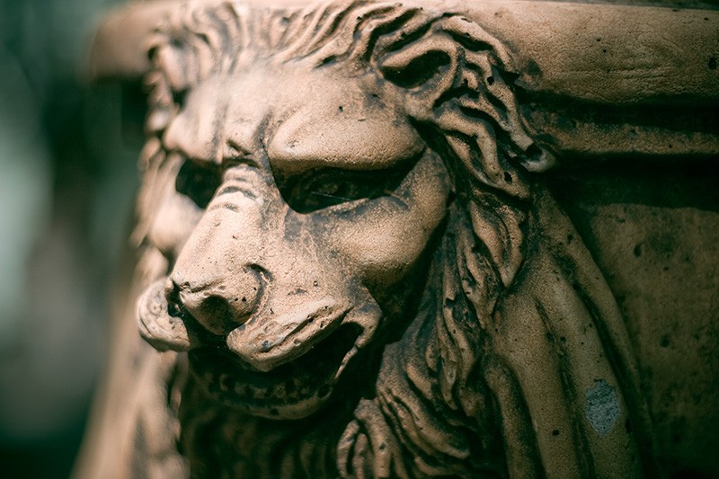 An ornamental lion on the side of a large pot.
