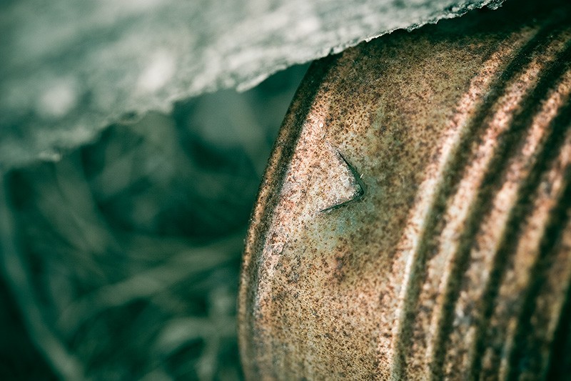 A rusty can with a V cut into it.