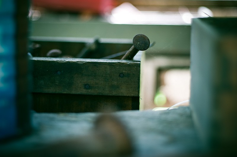 Nails in a wooden box, surrounded by other boxes.