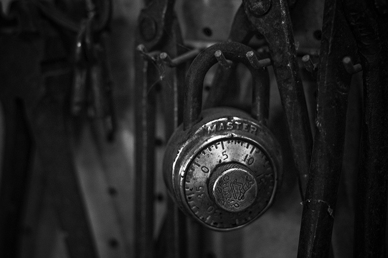 An antique Master lock hanging among numerous antique tools.