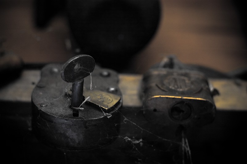 Two antique locks hanging from a beam.
