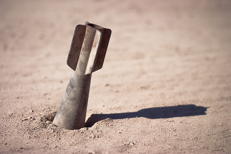 A cast-iron dummy bomb sticking out of the ground.