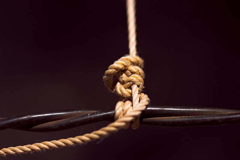 An orange string tied to a barbed-wire fence.