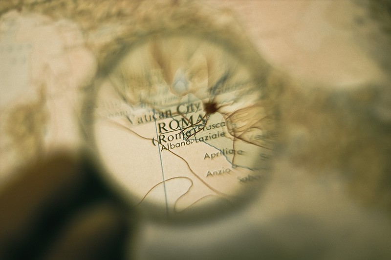 A magnifying glass showing Rome, Italy on a map.