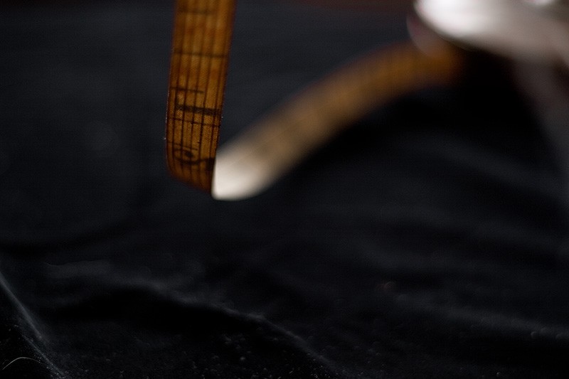 An antique tape measure showing the 12 inch mark.