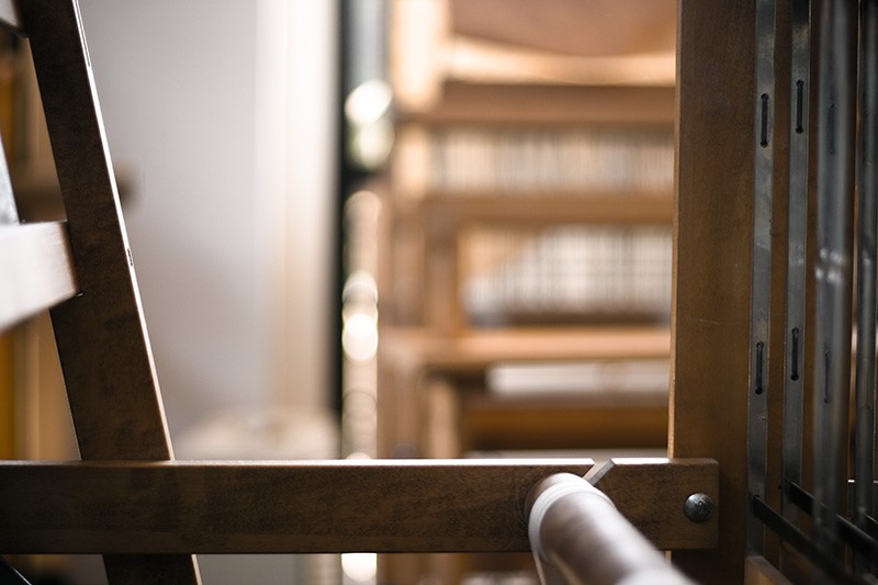 Part of a backlit loom, with other looms and a wall (and a windowframe) visible behind.