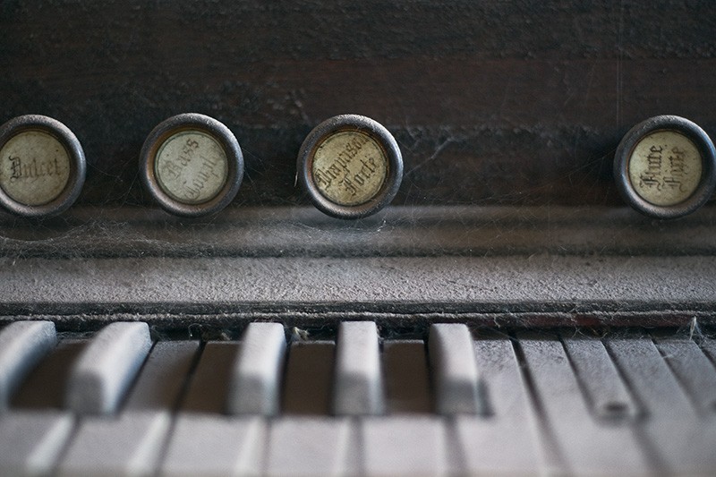 A detailed view of the keys and stops of a dust-covered antique organ.