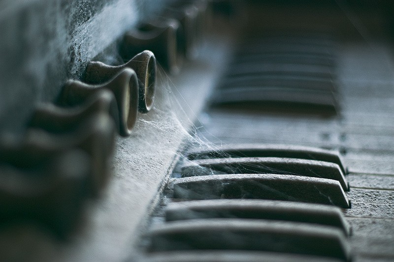 A dust- and spider web-covered organ, lit by moonlight.