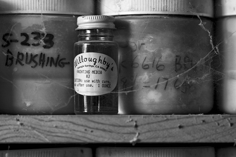 A small glass jar on a shelf, surrounded by larger containers.