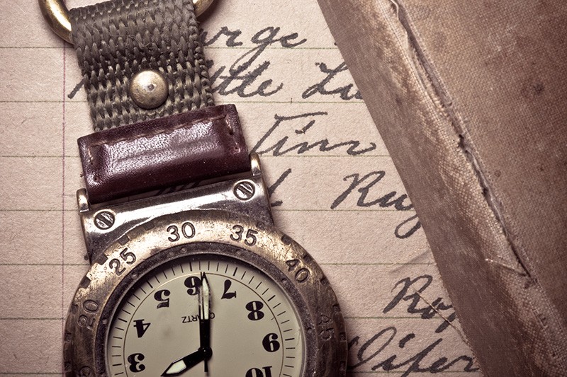 A well-worn pocket watch and book lying atop a handwritten letter.