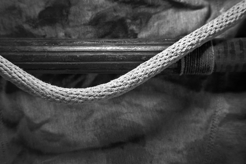 A thick rope bends into a curve above a carved bamboo pole.