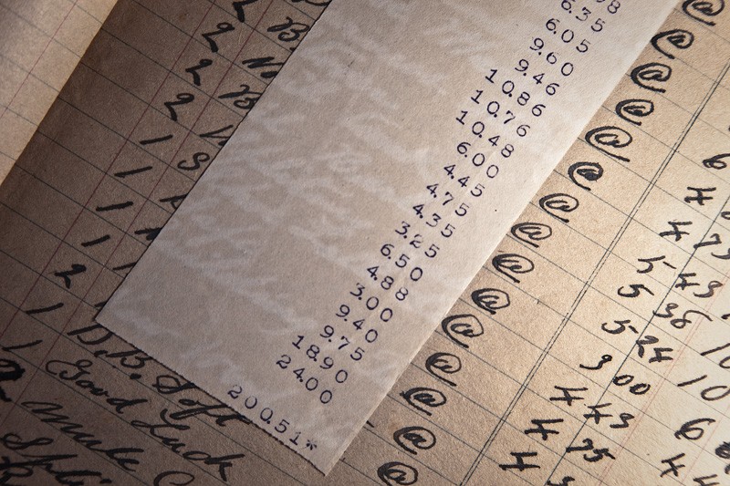 An antique ledger containing a receipt that has other writing imprinted onto it.