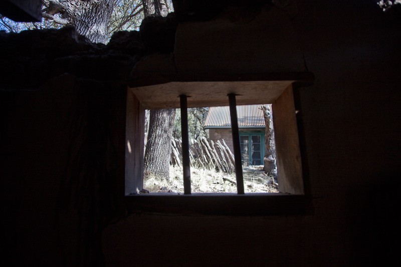 A view through the barred window of a partially collapsed structure.