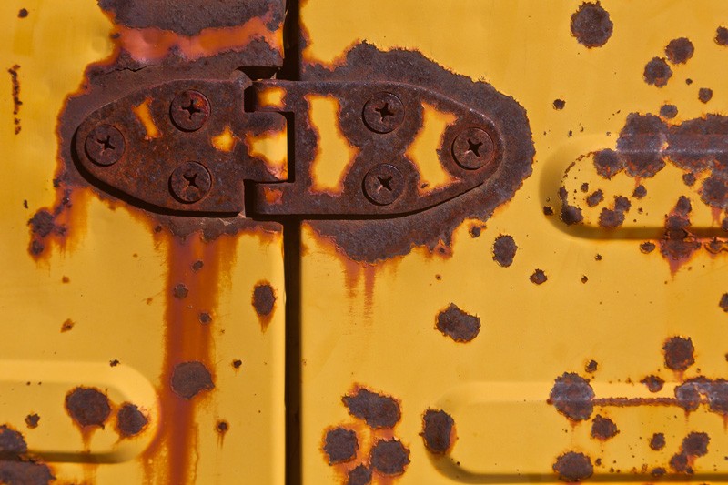 The hinge on the door of an old vehicle.