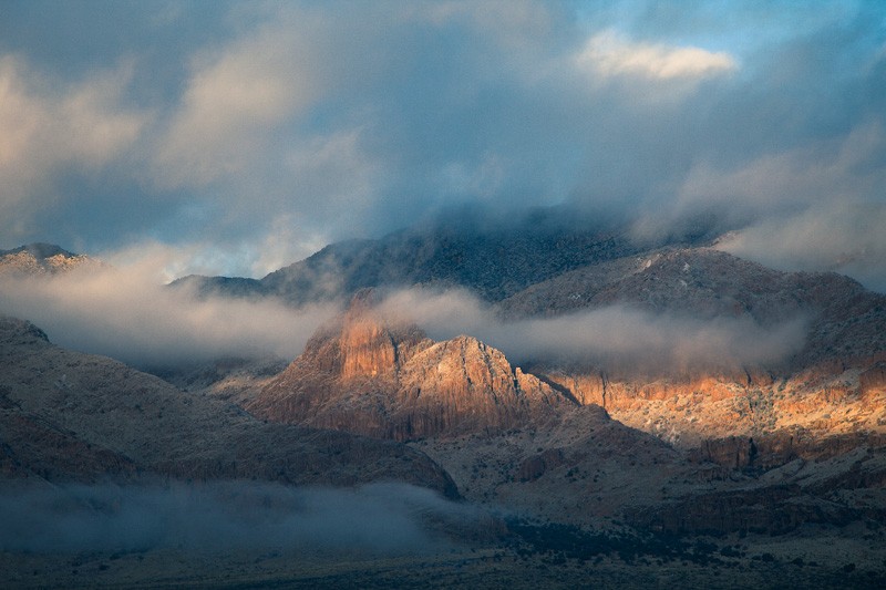 Sunlight coming through the clouds and striking Mangus Dome on the east slope of the Chiricahua Mountains.