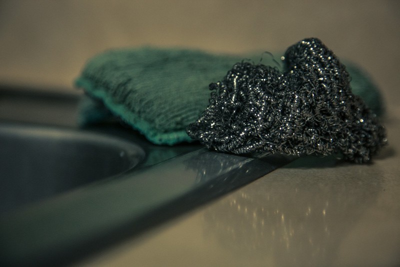 A pot scrubber and a sponge beside a sink.