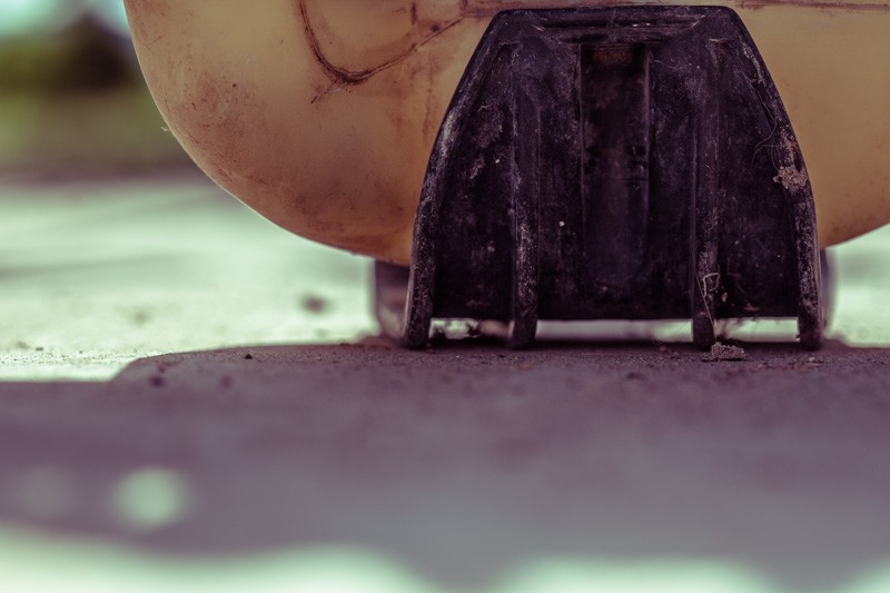 The base of a weedwhacker sitting out of commission.