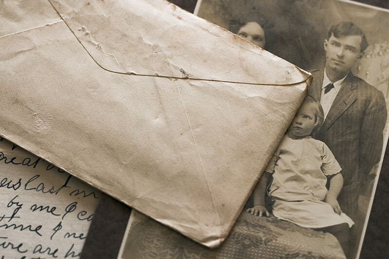 An unopened envelope sitting atop a family portrait and a letter.